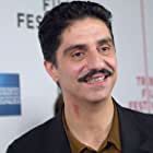 Simon Abkarian به عنوان Detainee on Monitor