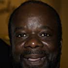 Joseph Marcell به عنوان Father Michael Lewis